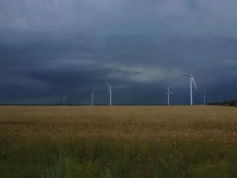 Wind generators are built on a wheat field against the background of a stormy Stock Photos