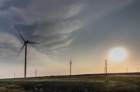 Wind generators on the background of the sky with clouds at sunset near the Stock Photos
