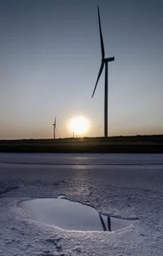 Wind generators reflected in a puddle of water on the background of the sky Stock Photos