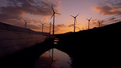 Wind generators silhouettes wide shot reflected on puddle. Stock Footage 97464897