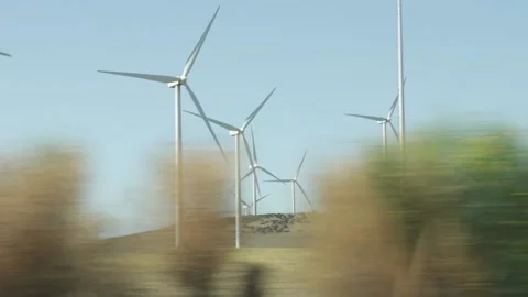 Wind generators spinning in operation viewed from a moving car Stock Footage 219735667