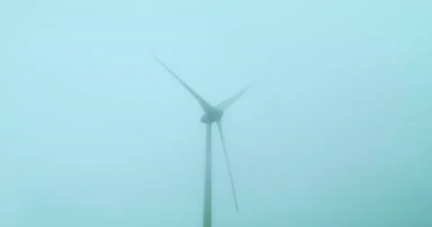 Wind machine producing alternative energy in foggy morning. Turbine rotating in Stock Footage 222217138