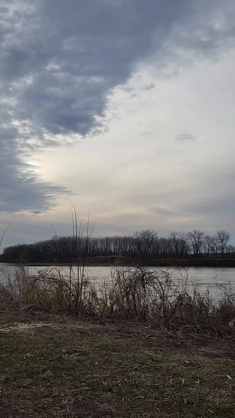 Wind Moving Dry Winter Grass Along Calm Missouri River Under Overcast Sky Stock Footage 330220309