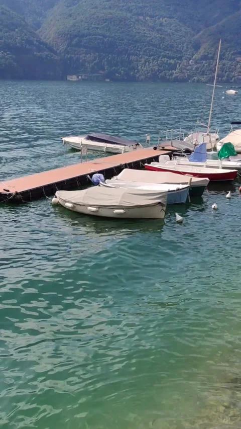 The wind is moving small boats moored in a romantich marina on Lake Como unde Stock Footage 221638555