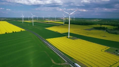 Wind power generators against the backdrop of flowering fields of rapeseed. Stock Footage 241647391