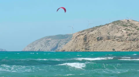 Wind Power - Mediterranean beach waves, kitesurfers &amp; cliff top wind farm Stock Footage 63119230