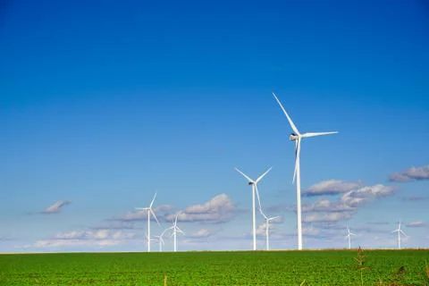 Wind power plant consisting of several wind turbines standing in a field agai Stock Photos