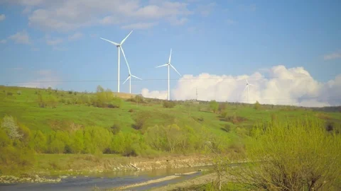 A wind power station on a mountain with sky and clouds and a river flowing below Stock Footage 74719587