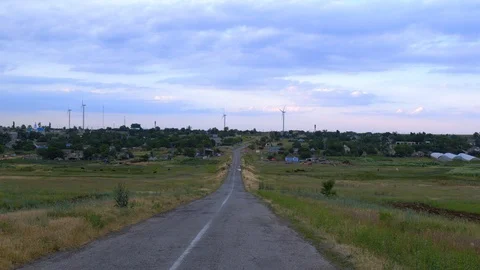 Wind power stations on the horizon in the middle of a rural road, windmills on a Stock Footage 112719374