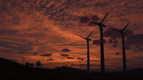 Wind-powered electricity generators against a sunset sky Stock Footage 203534408