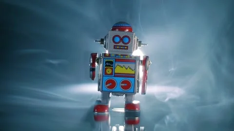 Wind-up robot walks on a glass surface in the rays of backlight in smoke Stock Footage 313148405