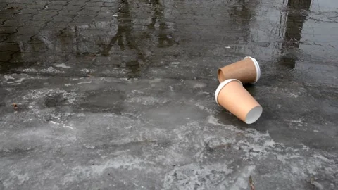 The wind rolls two discarded brown paper coffee cups down the sidewalk. Stock Footage 151026919