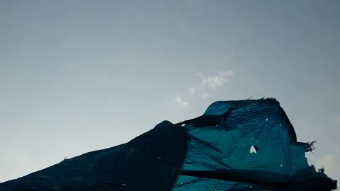 The wind ruffles a torn canvas of blue color Stock Footage 132667142