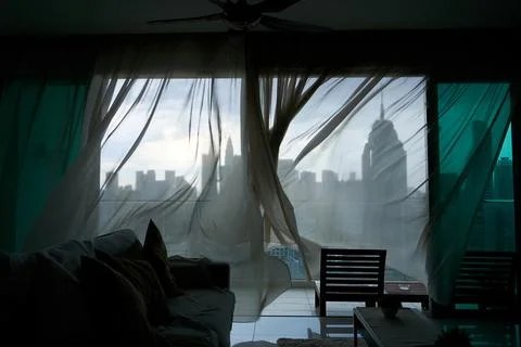 The wind rustles the curtain of the panoramic window with a cityscape Stock Photos