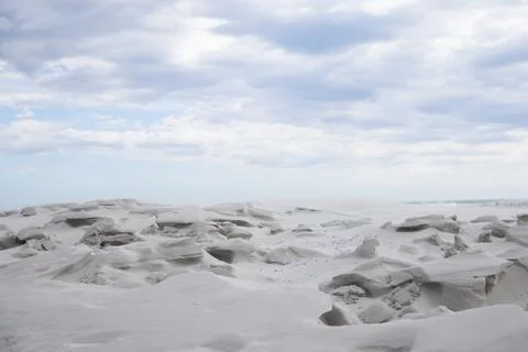 Wind-sculpted rocks are forming pebbled coastal sand flats with shallow hollows Stock Photos