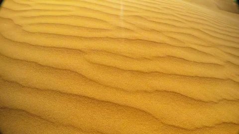 Wind slowly removes grain of yellow sand dunes like waves in desert thar top vie Stock Footage 90077941