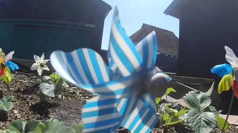 Wind spinners on veg patch in bright glinting sunlight on farm in slowmo Vídeos de archivo 333373825
