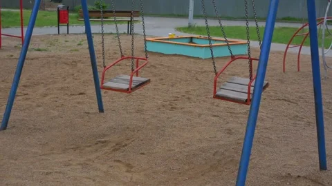 Wind sways red swings on chains on empty children playground Stock Footage 161127286