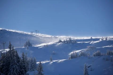 Wind sweeping snow across ski lift ridge Stock Photos