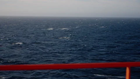 Wind-swept open ocean with rolling dark-blue waves and scattered whitecaps under Stock Footage 316774479