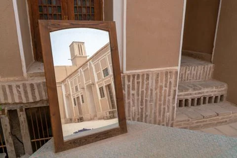 Wind tower, medieval cooling device, reflects in a mirror standing on a table in Stock Photos