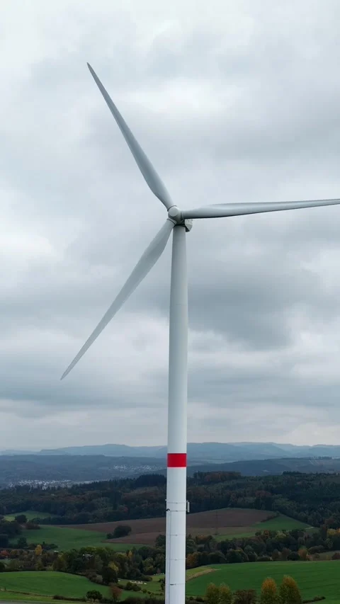 Wind turbine above a hilly landscape with fields and forest, seen from the ai Stock Footage 330298317