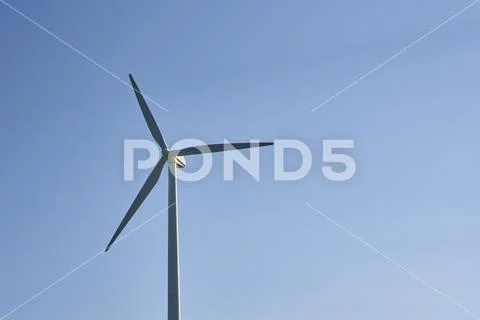 Wind turbine against blue sky. Wind power energy concept. Renewable energy fo Stock Photos