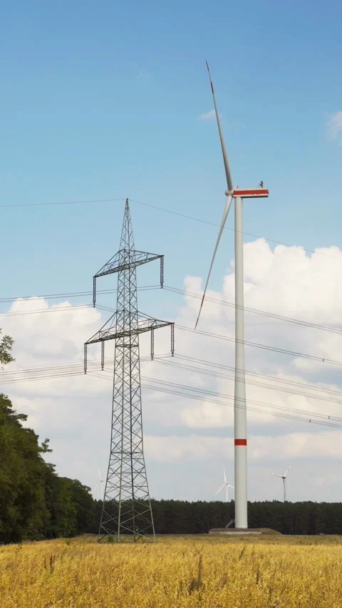 Wind turbine and high voltage tower on harvested field vertical for social media Stock Footage 204037962