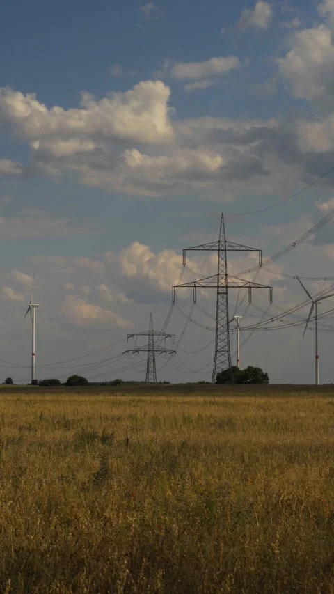 Wind turbine and high voltage tower on harvested field vertical for social media Stock Footage 204039468