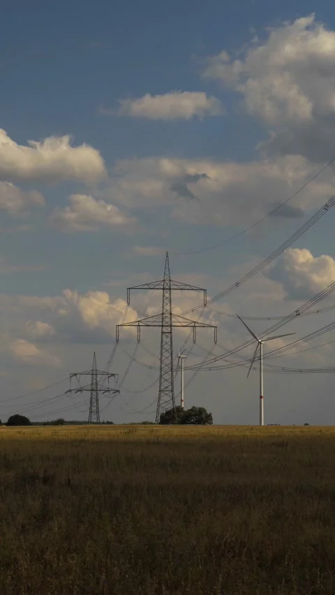 Wind turbine and high voltage tower on harvested field vertical for social media Stock Footage 204040341