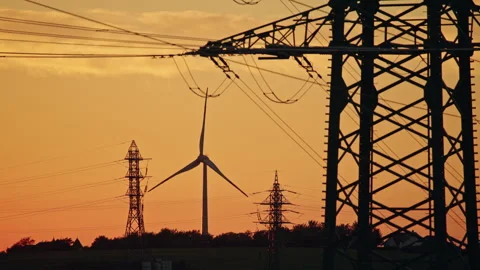 Wind Turbine and Power Lines Silhouetted at Sunset Stock Footage 344563642
