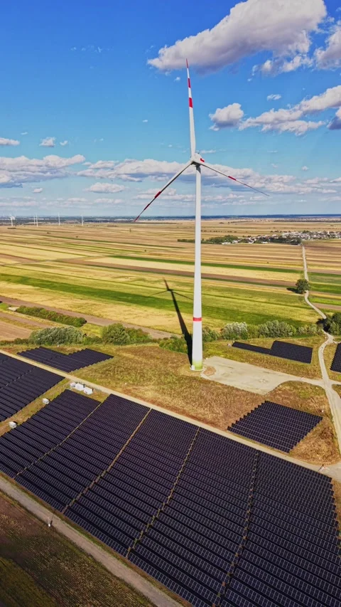 Wind turbine and solar panels in a field during the day Stock Footage 344535763