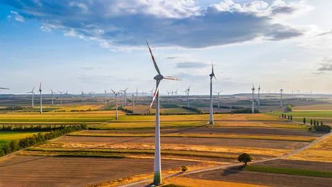 Wind turbine beside a track through crop fields. Red bands mark the blades .. Stock Photos