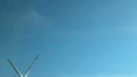 Wind turbine blade moving through an expansive blue sky on a bright summer day, Stock Footage 339090111
