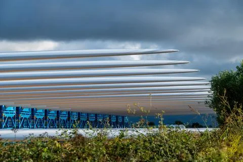 Wind turbine blade tips aligned above transport racks Foto stock