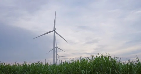 Wind turbine blades rotating under cloudy blue sky at renewable energy farm, Stock Footage 328697130