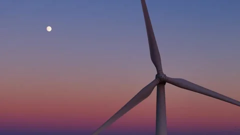 Wind turbine blades spinning, creating renewable energy below a moon in a Stock Footage 328483501
