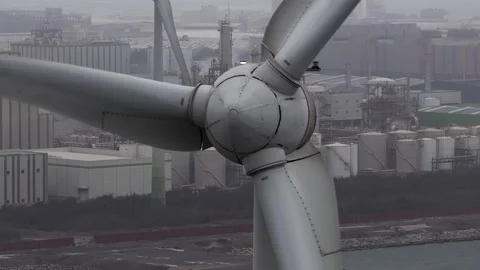 Wind turbine blades spinning generating sustainable energy near industrial Video stock 330124893