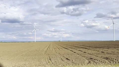 Wind Turbine Casting Long Shadow Across Agricultural Field at Sunset Video stock 335215297