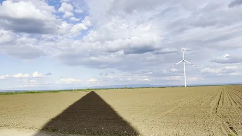 Wind Turbine Casting Long Shadow Across Agricultural Field at Sunset 스톡 동영상 335215323