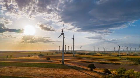 Wind turbine casting a shadow beside a farm track. The sun glows through cl.. Stock Photos