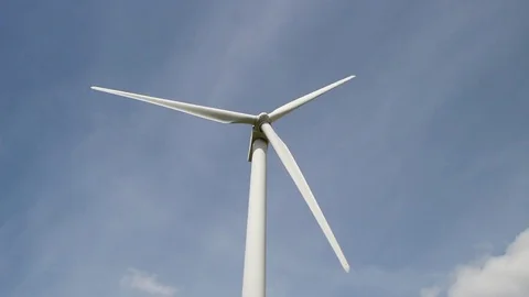 Wind turbine in clear blue sky turning - view from the ground Stock Footage 75535178