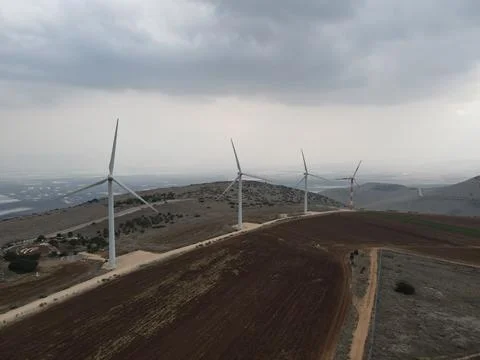 Wind turbine farm on the side of a mountain with storm clouds around Stock Photos