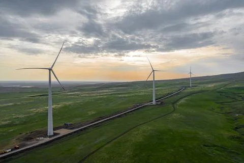 Wind turbine farm at sunset with dramatic sky. Producing alernative energy Stock Photos