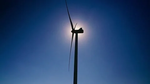 Wind turbine in a field blocking the sun. Windmill with huge blades produces Stock Footage 222417455