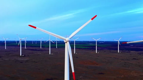 Wind turbine in focus with farm in background at dusk 스톡 동영상 333837876