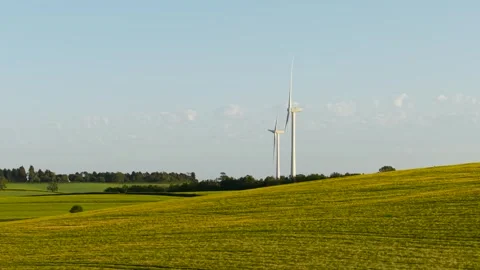 Wind turbine generating renewable electricity above rolling green fields. Clean Video stock 337417012