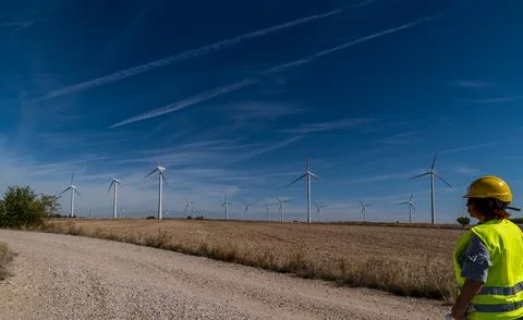 Wind turbine inspector working at a wind farm with scattered clouds.2 Stock Photos