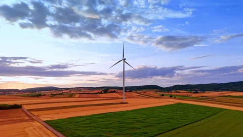 Wind turbine operating in rural fields before distant hills. Drone shot of a Stock Footage 339014920