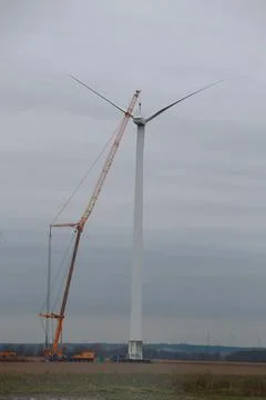 A wind turbine is in the process of being constructed with the help of a crane Stock Photos